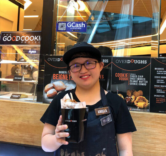 Employee with Down Syndrome smiling and holding the food served at their store